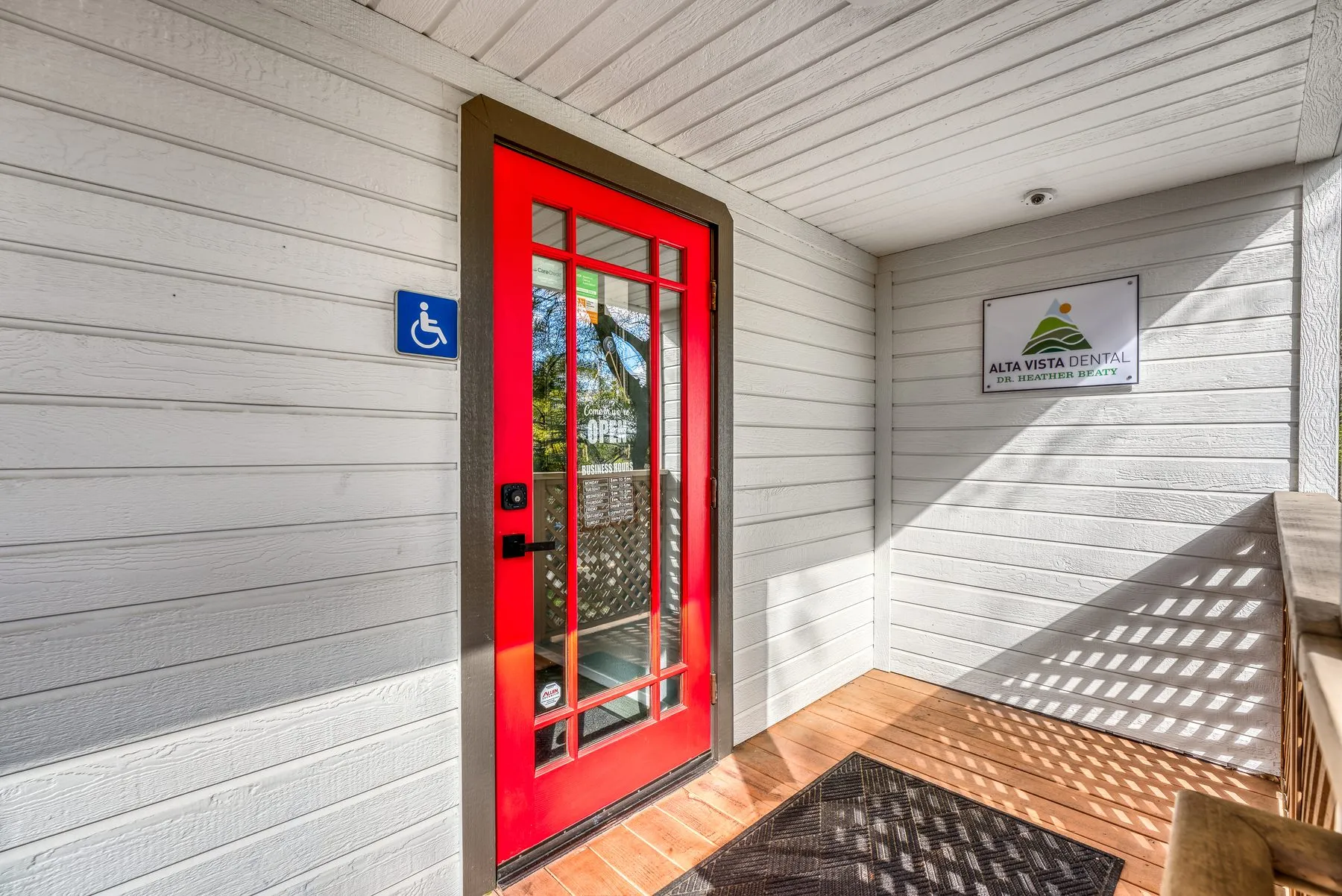 The red front door and covered porch at the accessible entrance to the office